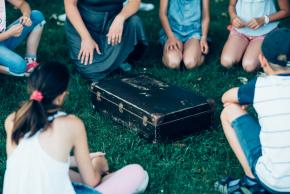 Musikvermittlung Veronika Großberger Schülerinnen und Schüler sitzen um Koffer auf Wiese, Ernst Krenek